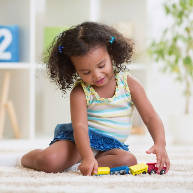 A young girl is playing with toys on a rug