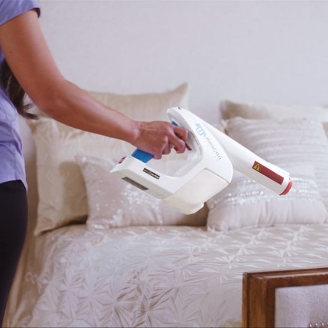 A person is shown using the Electrostatic Handheld Sprayer over a bed